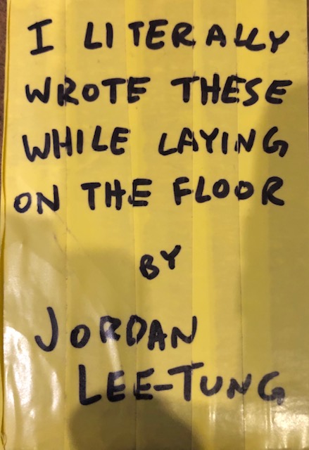 Yellow taped cover with black marker writing reading "I literally wrote these while laying on the floor by Jordan Lee-Tung"