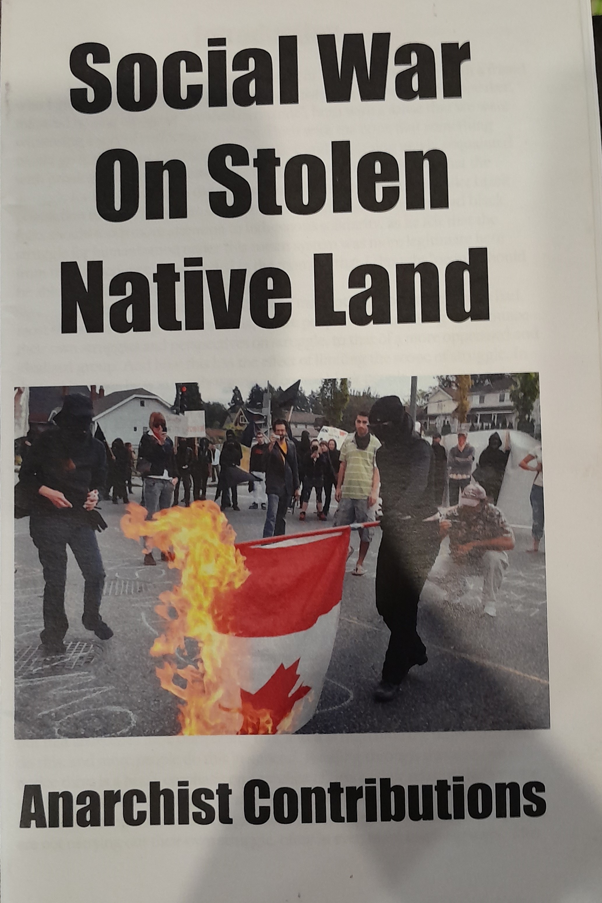 The title is written in black sans-serif text on a white background that says "Social War On Stolen Native Land", accompanied by a colour photograph of two individuals dressed in all black burning a Canadian flag at an indigenous gathering. Below, in black 