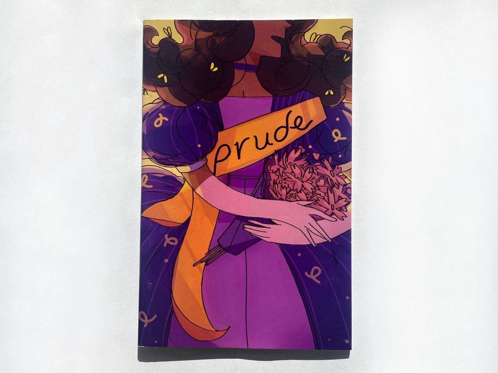 Cover of Prude zine, which shows a person with long brown hair wearing a purple dress clutching a bouquet of pink flowers with a yellow sash that says Prude